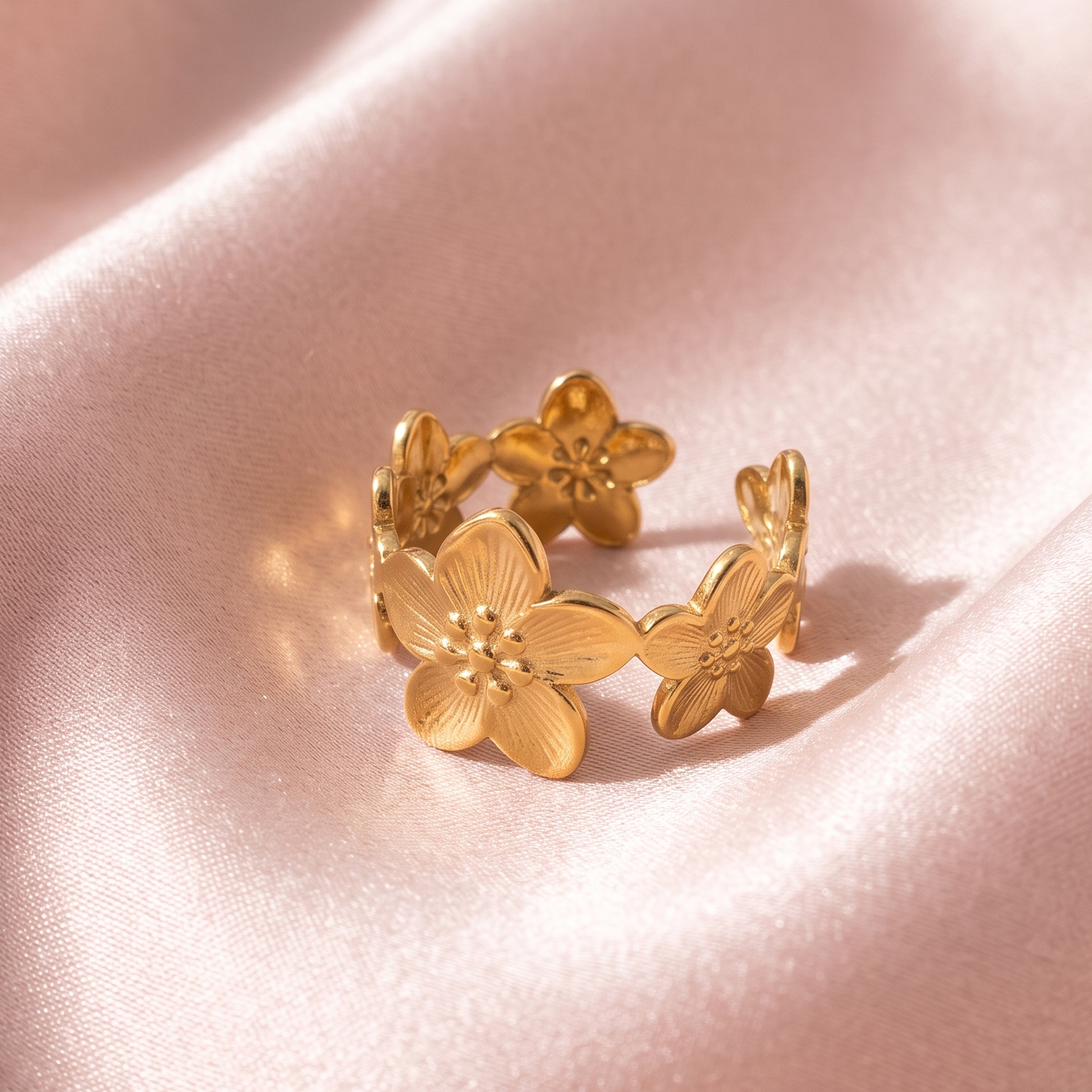 Bague Couronne de Fleurs dorée posée sur soie rose, vue détaillée